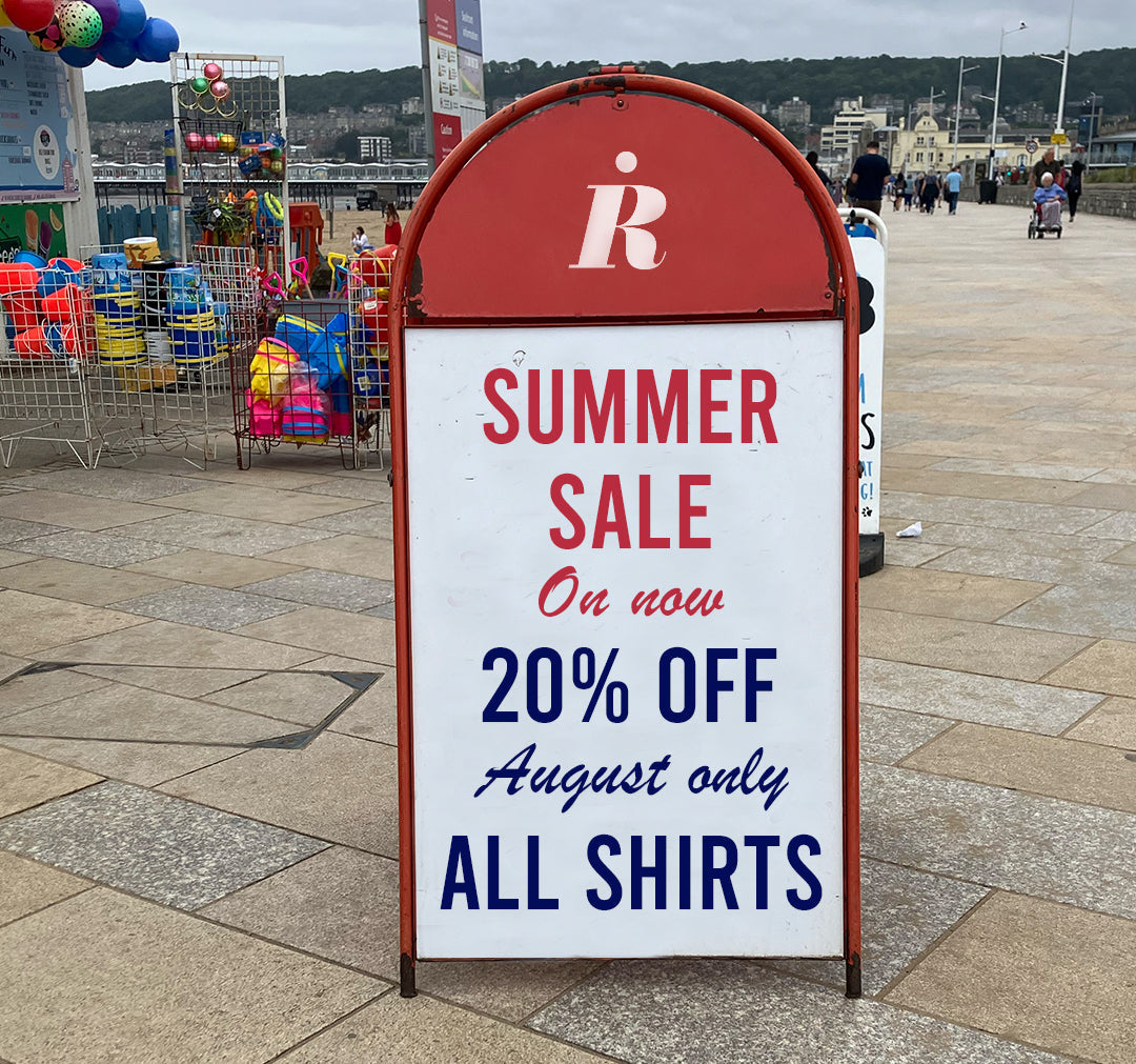 Outdoor sign advertising a summer sale with a red and white design on a pavement.